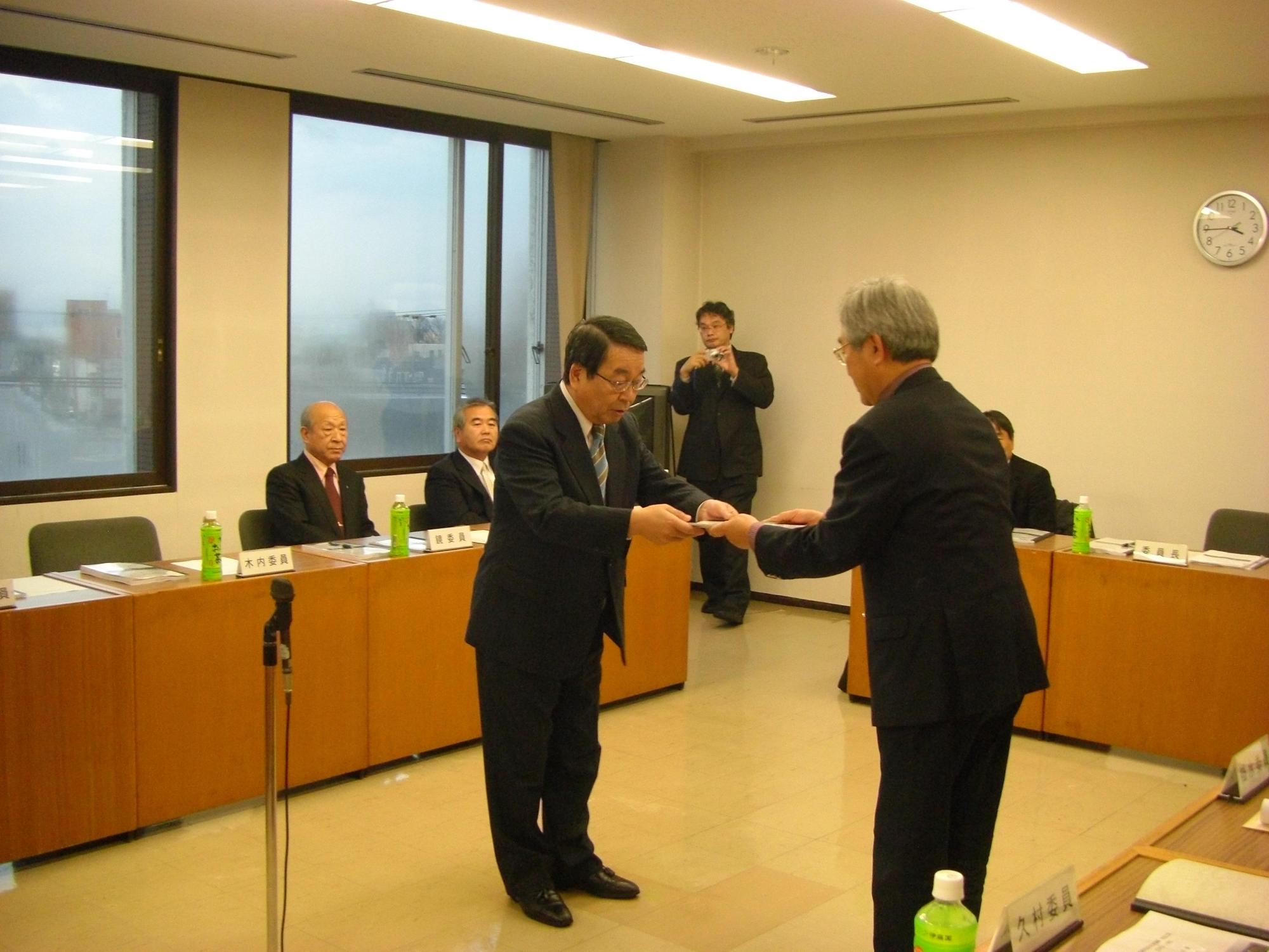 札幌恵庭自転車道線延伸ルート検討委員会の泉谷委員長かより原田市長へ提言書を手渡ししている写真