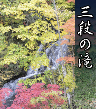 紅葉した木々の後ろに見える三段の滝の写真
