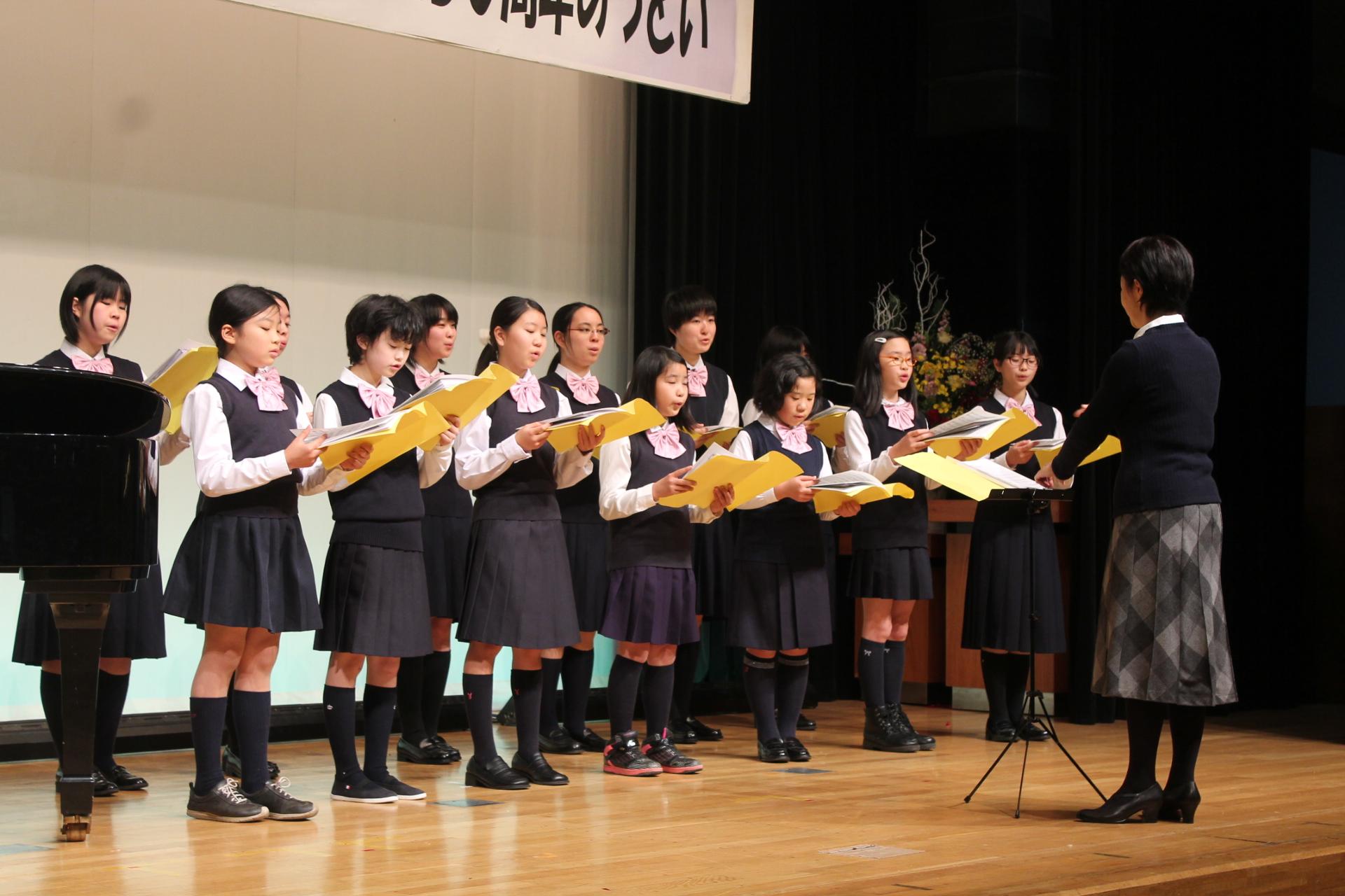 ステージの上で合唱している女子学生達の写真