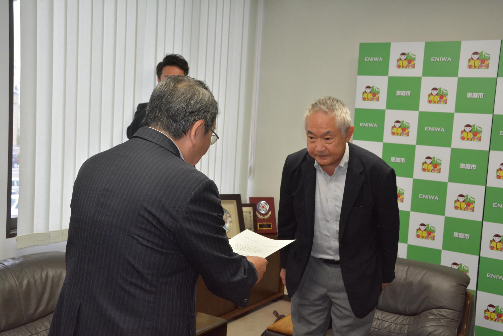 恵庭市まちづくり基本条例市民検討委員会高橋修委員長より原田市長へ恵庭市まちづくり基本条例検証報告書を提出している写真