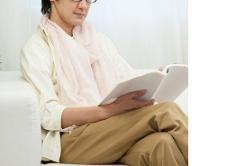 成人女性が白いソファに座って広報誌を読んでいる写真