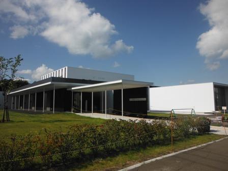 青空と芝生に囲まれた施設入口側からの外観写真