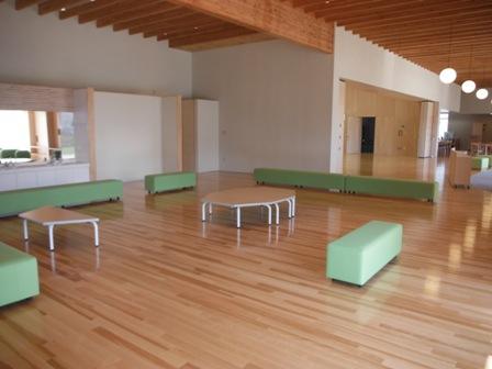 八角形や台形のテーブルと緑色のソファーが設置されたプレイスペースの写真