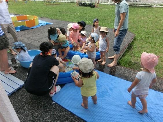 地域交流保育で子供たちがビニールプールで遊んでいる写真