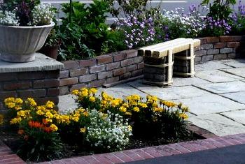 花壇には色とりどりの花が植えられ、手作りのベンチが置かれているふれあい工房前の写真