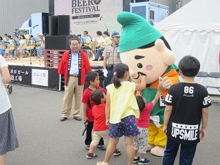 会場にて子ども達と触れ合うえびすくんを笑顔で見る原田市長の写真