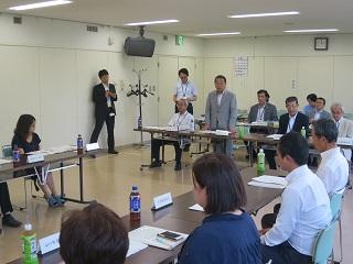 市民会館で開催された審議会で挨拶をする原田市長と出席者の写真