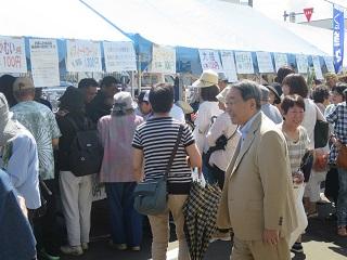 大勢の来場者でにぎわう会場内の出店を見て歩く原田市長の写真