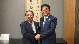 安倍内閣総理大臣と握手をし記念撮影している写真