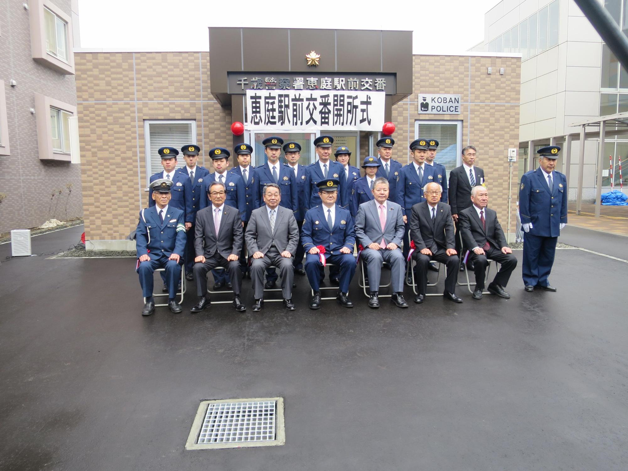 恵庭駅前交番の前で警察職員と一緒に記念撮影している写真