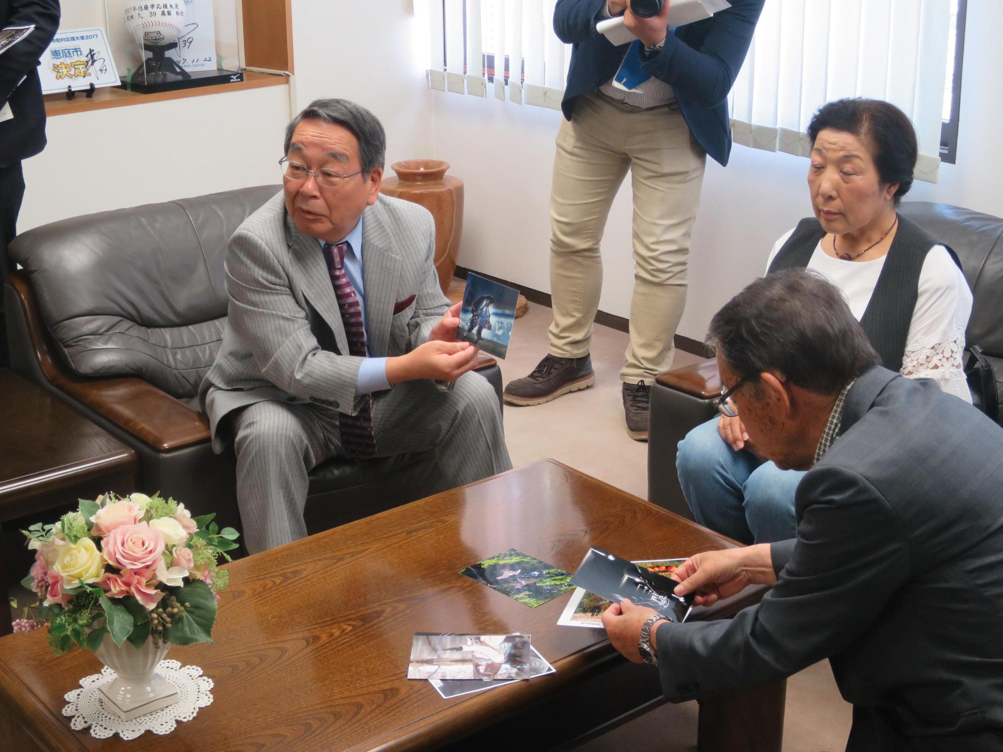 恵庭写真協会の方の入選写真を手に取って見ている原田市長の写真