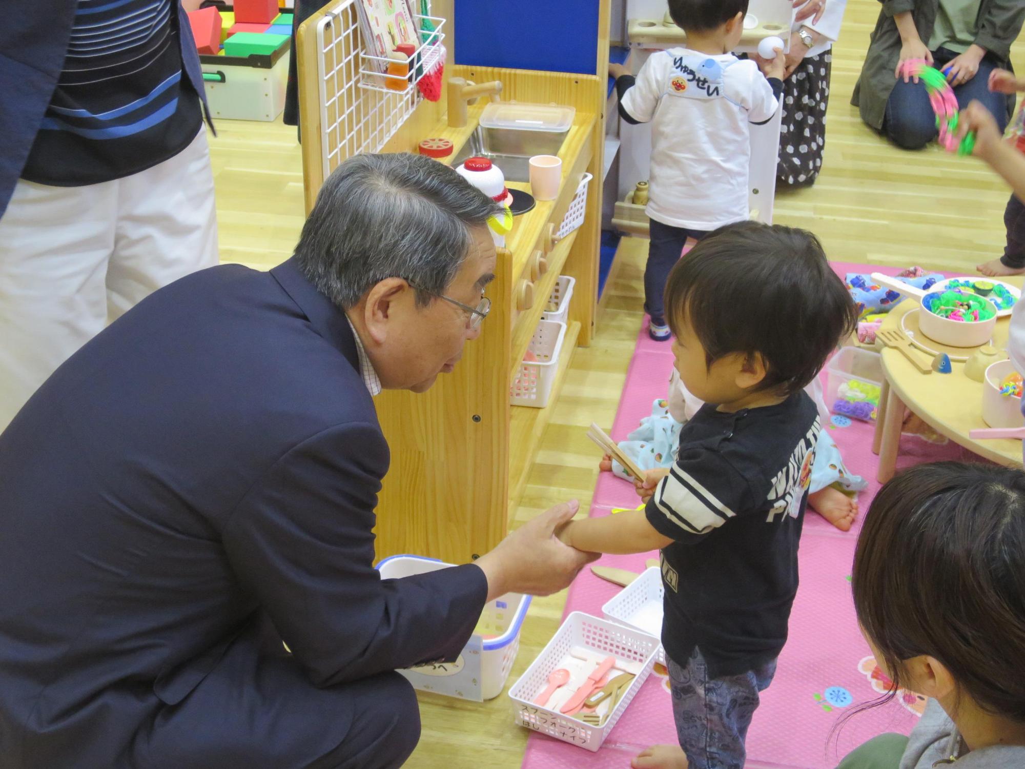 イベントに参加している幼児と握手をしている原田市長の写真