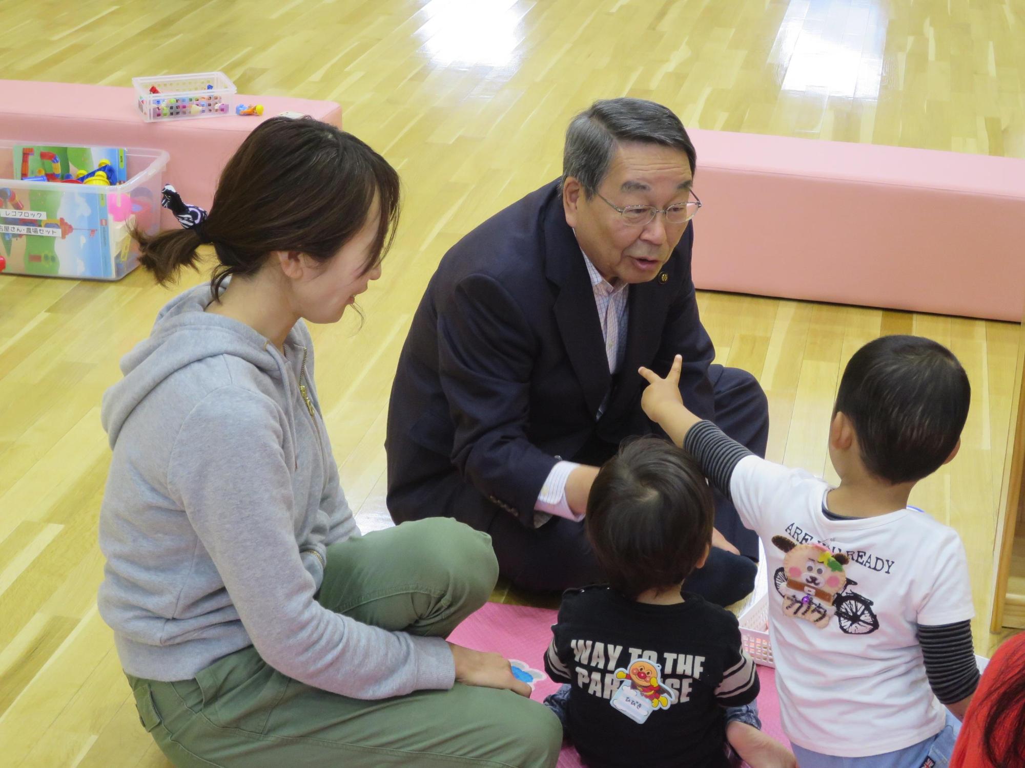 イベントに参加している幼児とお母さんとお話をしている原田市長の写真
