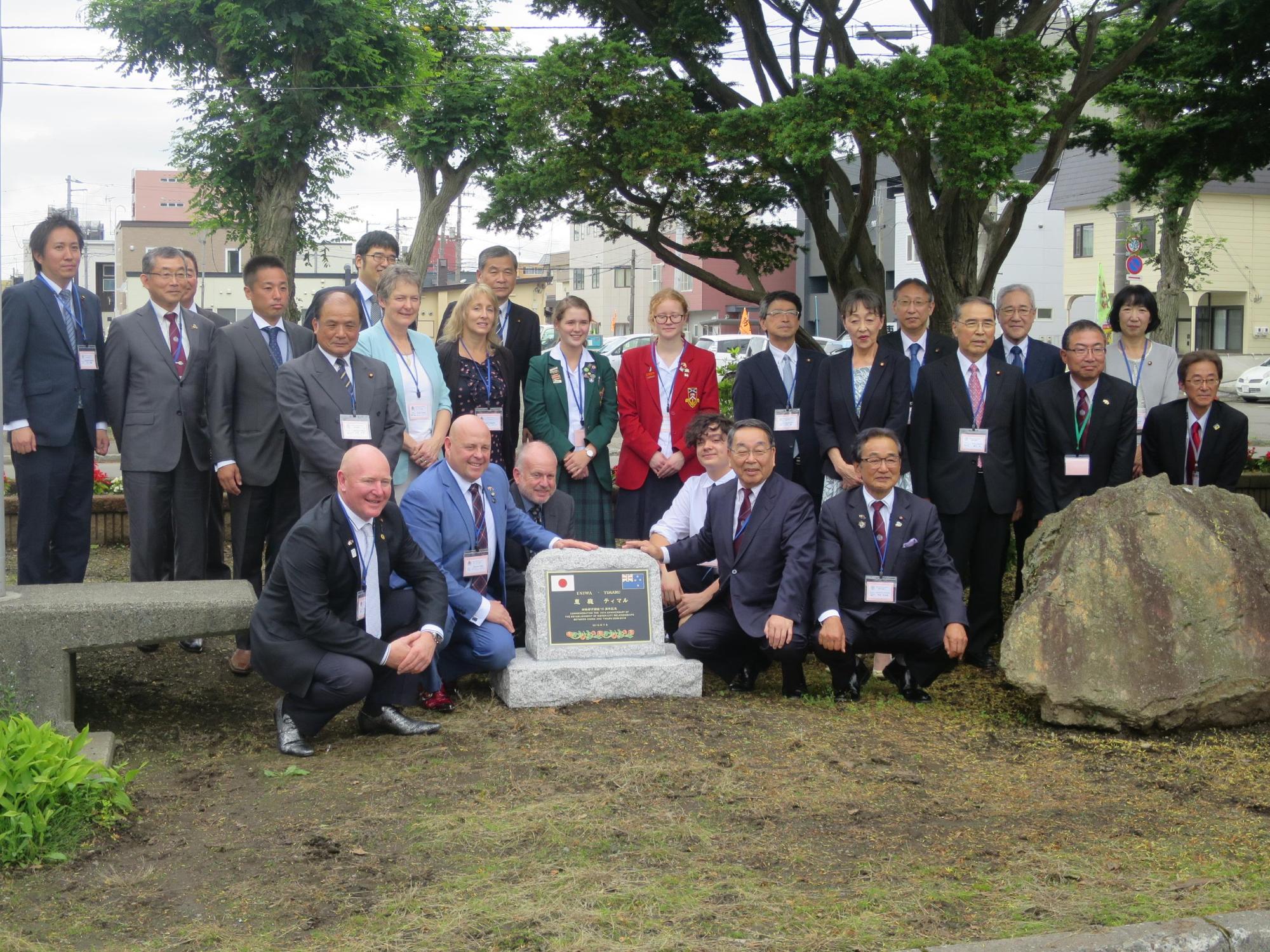 記念碑とともに記念撮影をする原田市長らと訪問団の写真