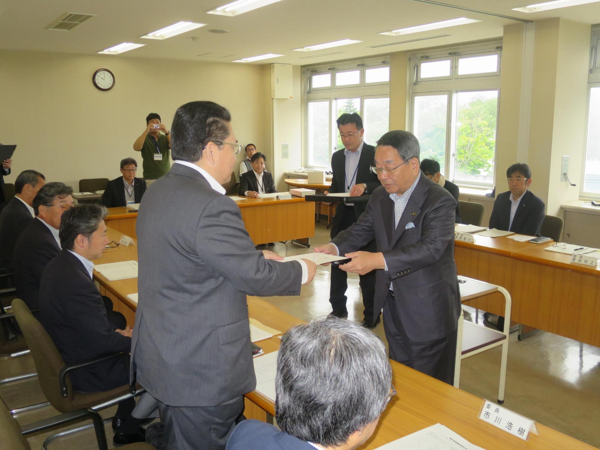 審議会にて委員へ委嘱状を交付する原田市長の写真
