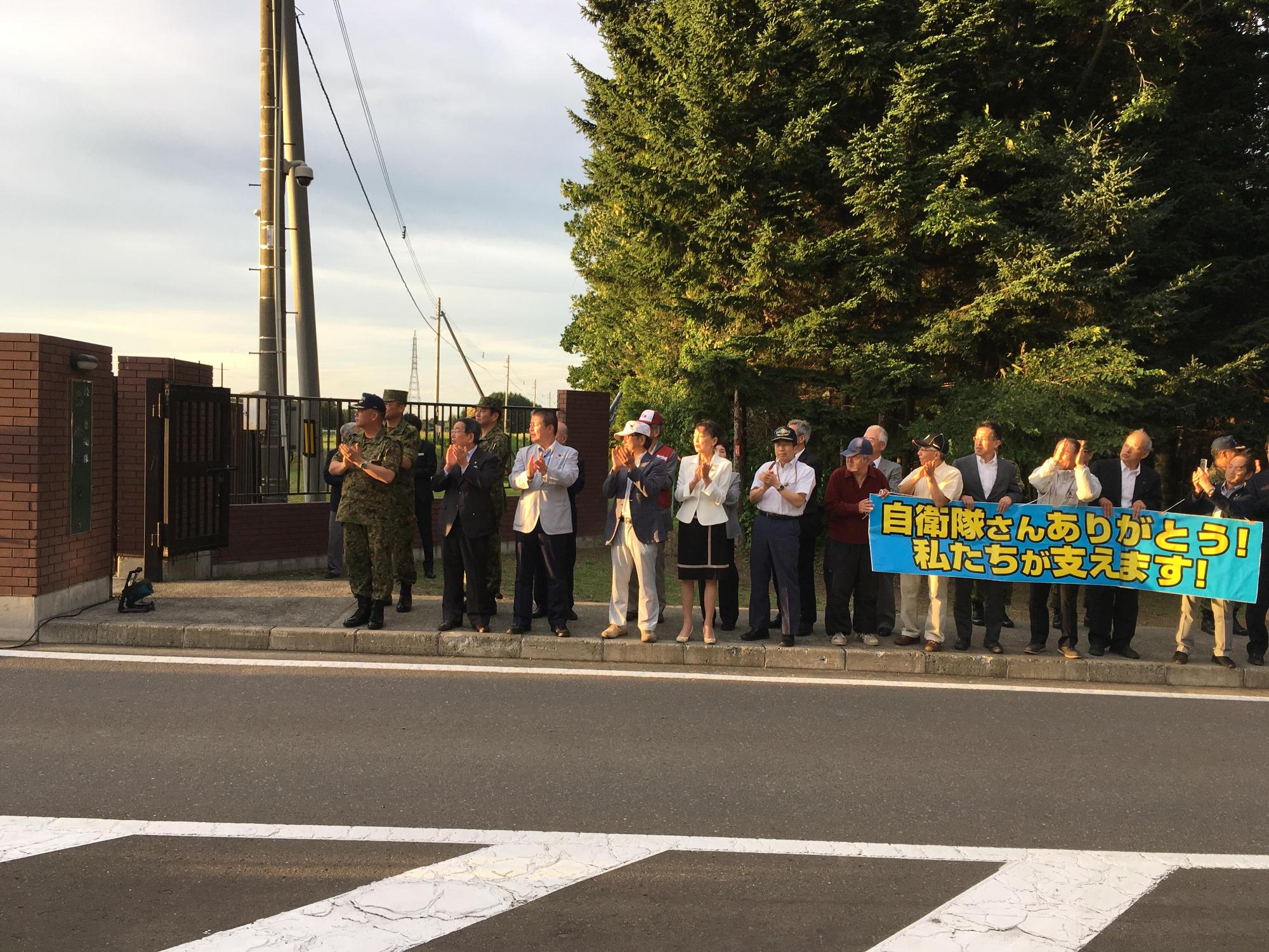 島松駐屯地から出発する支援隊へ沿道から激励する原田市長らの写真