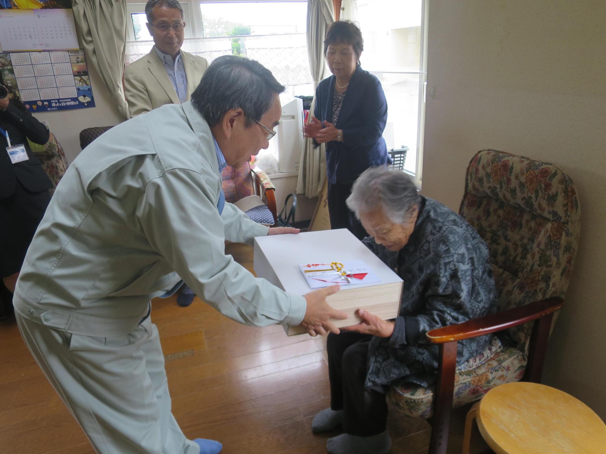 今年度100歳の誕生日を迎えられる方へ記念品を授与している原田市長の写真