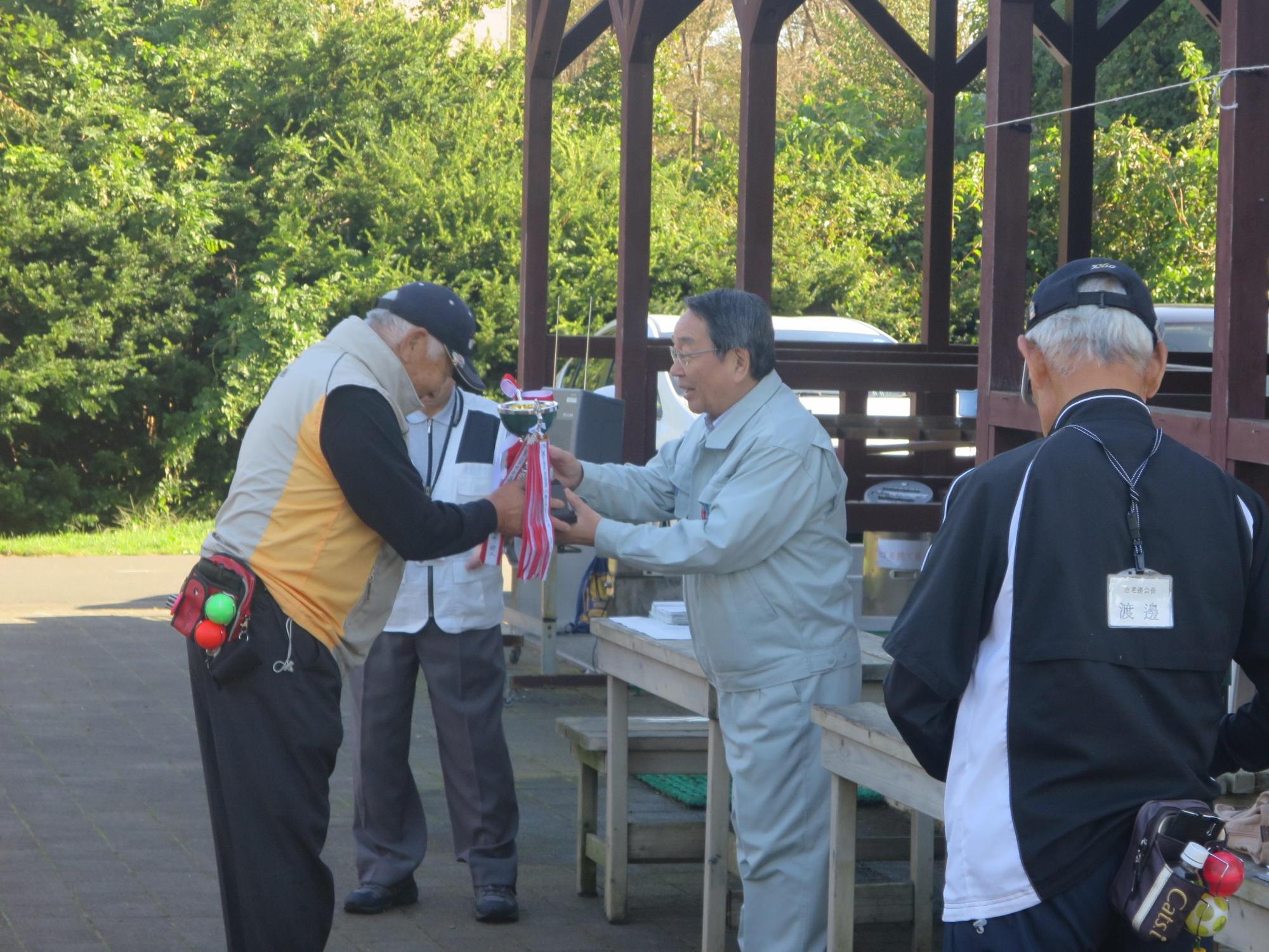 老人クラブPG大会にて入賞者へトロフィを授与している原田市長の写真