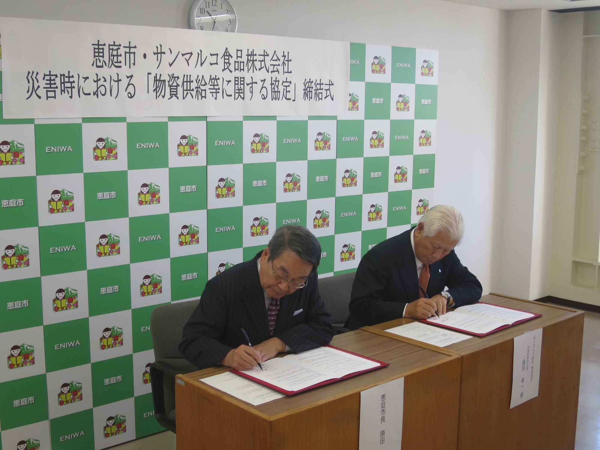 災害時応援協定締結式で署名を行う原田市長とサンマルコ食品株式会社