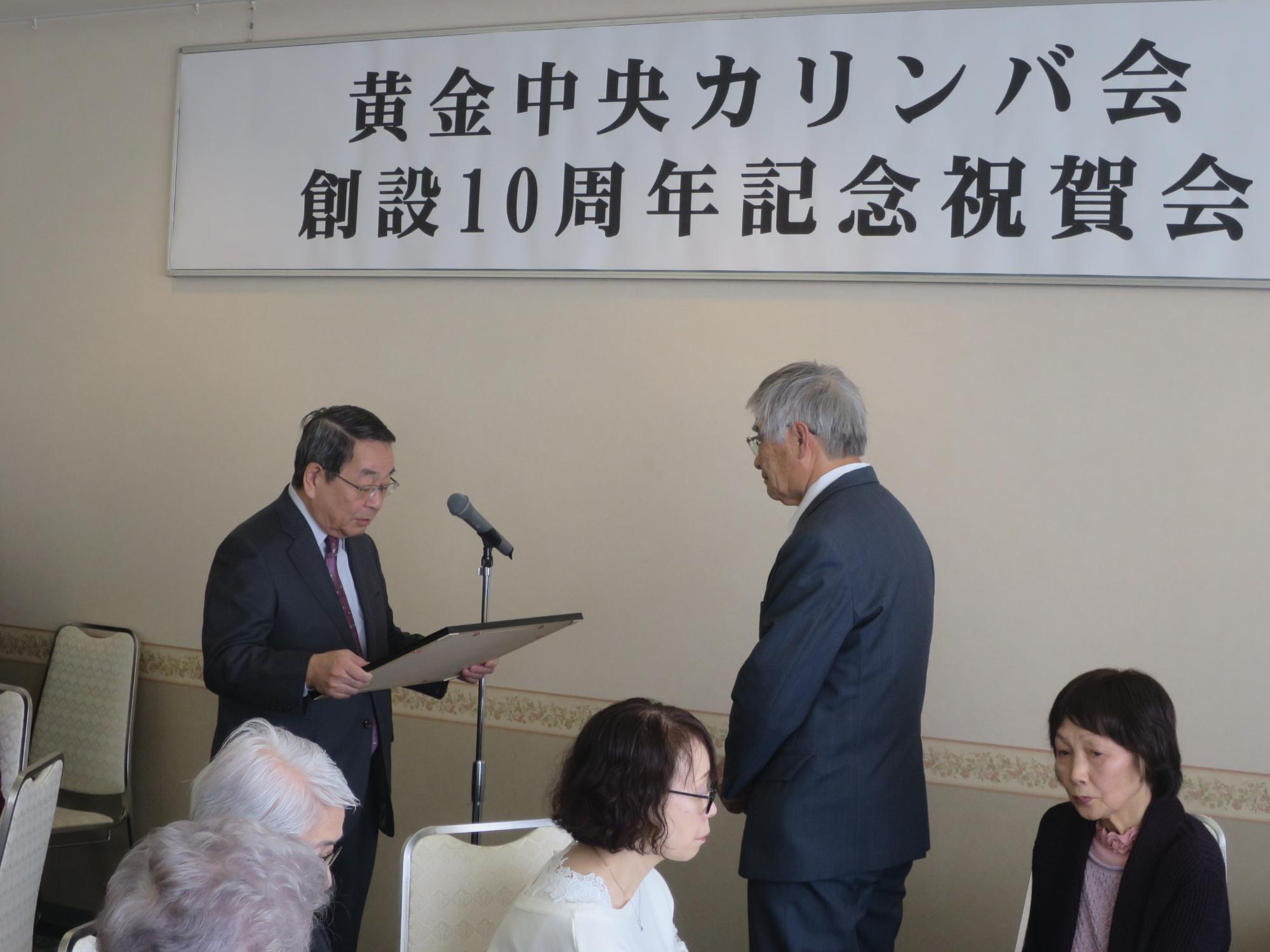 黄金中央カリンバ会創立10周年記念祝賀会で表彰状を渡す原田市長