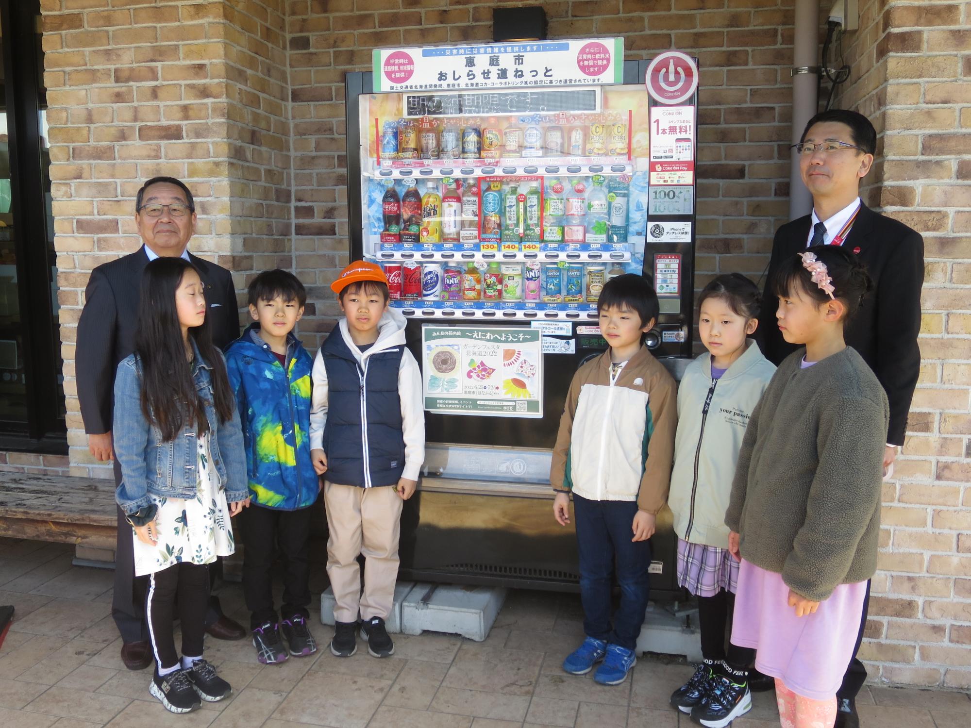 自動販売機の前で子どもたちと記念撮影する原田市長