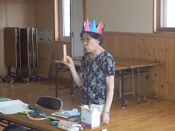 北村さんが折り紙で出来た王冠を被り、実演している写真