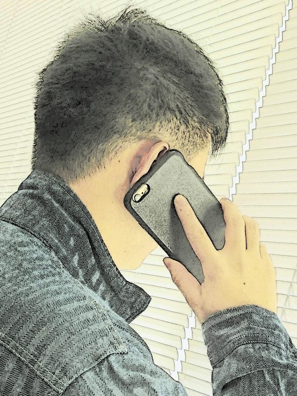 携帯電話で電話をかけている男性の写真